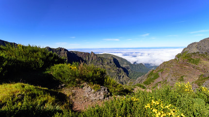 Wide angle shot of Mountain peaks against blue sky with white clouds on a beautiful summer day. Near Pico de Areeiro (Arieiro), Central Madeira, Portugal, Europ