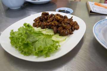 grilled pork intestine with cucumber and lettuce on white plastic dish and stainless steel desk
