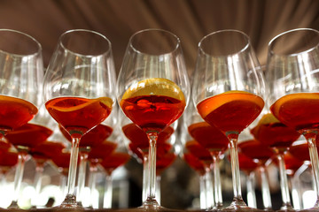 A lot of cocktails at the bar at the wedding party. Glasses with apperol and with a slice of lemon close-up
