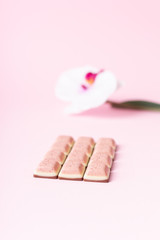 Pink chocolate bar and flower on pink background. Ruby new chocolate. New pink sweet dessert