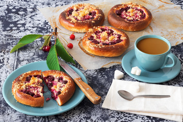 Table with yeasty sweet pastry with fresh cherries and streusel topping, cup of tea and few cubes of sugar. Summer fresh fruit appetizer.
