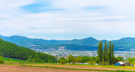 Panoramic rural landscape with mountains. Vast blue sky and white clouds over farmland field in a beautiful sunny day in springtime.