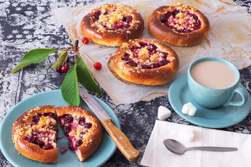Table with yeasty sweet pastry with fresh cherries and streusel topping, cup of tea and few cubes of sugar. Summer fresh fruit appetizer.