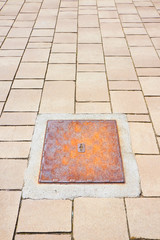 Rusty iron cast manholes in a modern stone paving