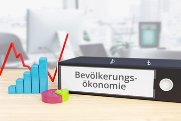 Bevölkerungsökonomie – Finanzen/Wirtschaft. Ordner auf Schreibtisch mit Beschriftung neben Diagrammen. Business