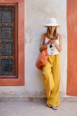 Stylish woman texting in traditional moroccan riad