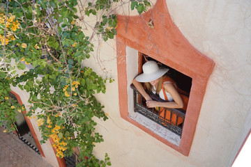 Stylish woman looking out traditioanl Moroccan window