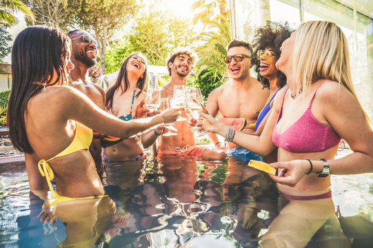Happy friends drinking champagne at swimming pool party