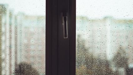 rain drops on the window. rainy wet window. buildings city on background.