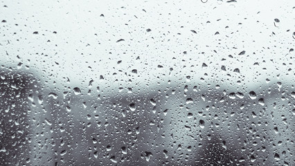 Rainy window. raindrops on a window glass at night. dark blue wet, drops of water rain on glass background. concept of autumn weather.