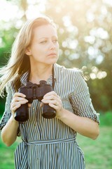 Attractive woman having binoculars outdoor in nature.