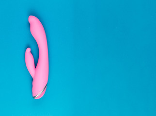 Beautiful evenly lit pink dildo on a plain blue background with copy space.