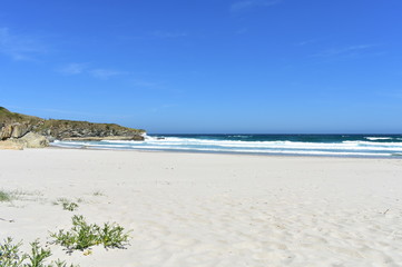 Wild beach with white sand, rocks and waves. Lugo, Spain.