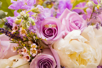 bouquet of pink and purple roses with wedding ring 