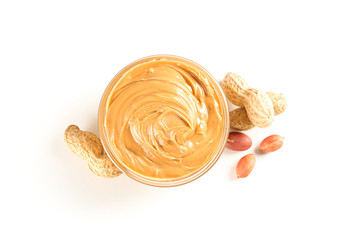 Creamy peanut butter in glass bowl and peanut isolated on white background, top view. A traditional...