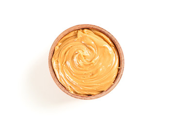 Creamy peanut butter in wooden bowl isolated on white background, top view. A traditional product of American cuisine