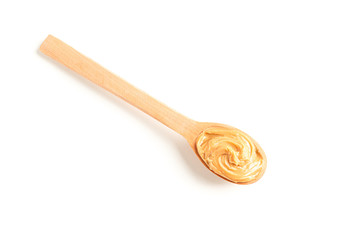 Creamy peanut butter in wooden spoon isolated on white background, top view. A traditional product of American cuisine