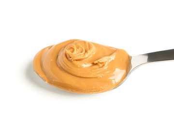 Creamy peanut butter in spoon isolated on white background, closeup. A traditional product of American cuisine