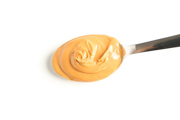 Creamy peanut butter in spoon isolated on white background, top view. A traditional product of...