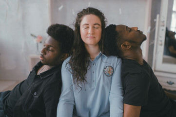 Multicultural love and relationships concept. Young white woman sits between two sleeping african dark skinned men. Soft focus studio portrait of interracial embracing couple. Interracial friendship.