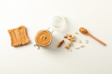 Flat lay composition with peanut butter sandwich, glass jar, peanut and spoon on white background,...