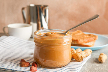 Yummy peanut butter breakfast on grey table against light brown background, space for text