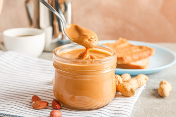 Yummy peanut butter breakfast on grey table against light brown background, space for text