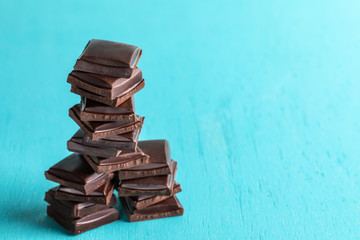 Vertical stack of squared slices of chocolate on turquoise  background.