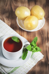 Сup with tea, mint and lemon on the old table