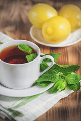 Cup with tea, mint and lemon on the old table