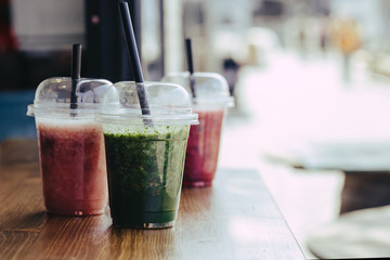 Colorful Sweet smoothie in plastic cups on wooden table