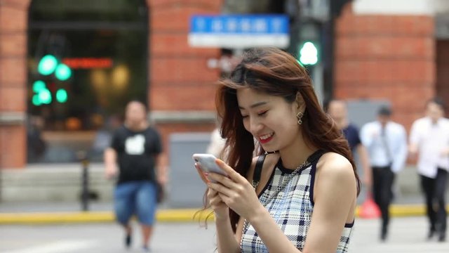 Asian girl playing mobile phone on the streets of Shanghai