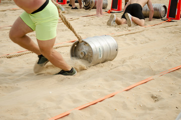 A man in shorts pulls a rope tied with rope over the sand.