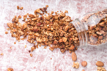 honey granola with nuts in bulk from glass jar on table, horizontal