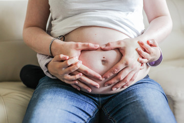 pregnant woman touching her belly with hands