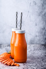 two glass bottle with carrot smoothie on table