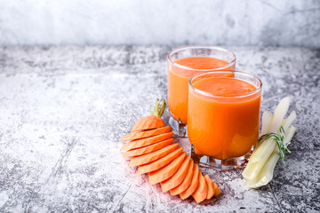 Two glass, low glasses on table, with carrot and celery smoothie
