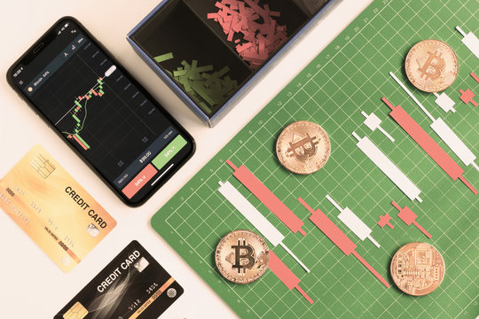 Top view, Candlestick chart make from color paper white and red on Green board with grid lines with smartphone credit card, investment, trading, stock, finance concept