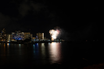 Fototapeta na wymiar Friday night fireworks at Waikiki Beach, Honolulu cityscape at night, with negative space of blackness.