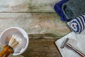 Traditional wet shaving supplies in rustic wooden table. Retro safety razor and lathered shaving brush. With copy space.