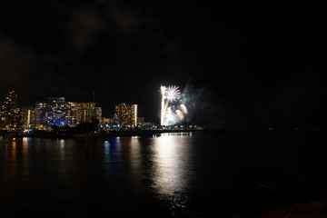Naklejka na ściany i meble Friday night fireworks at Waikiki Beach, Honolulu cityscape at night, with negative space of blackness.
