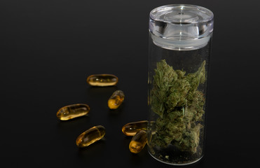 Side view, glass jar with cannabis with thc oil pills on black background