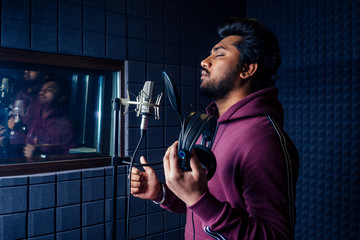 professional singing indian men headphones sound modern studio violet background recording song.