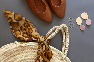 Fashionable accessories: straw bag with leopard print scarf, vintage brown leather shoes, gold...