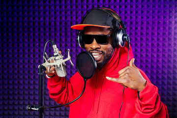 afro american man headphones in a cap and a hood sunglasses recording hip hop song track.