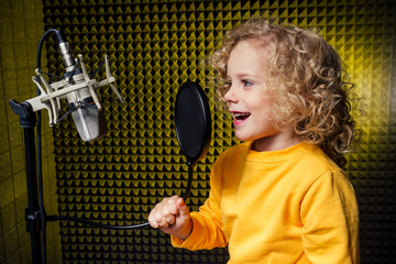 girl blonde curly hair style star singer artist in a yellow blouse with headphone recording new...