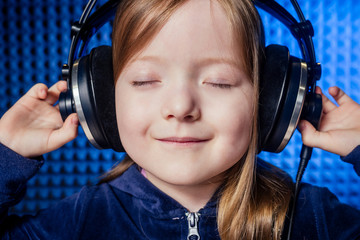 girl star singer artist in a black blouse with headphone recording new song with microphone.
