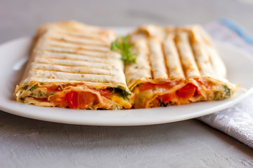 Suluguni in pita bread with greens and tomatoes on a white plate