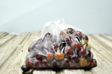 half kilo of olives in a plastic bag on a wood background. image