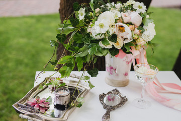 Botanic bridal chic. Bouquet with silk ribbons and greenery, mirror, succulents, wedding rings and engagement ring on vintage table.